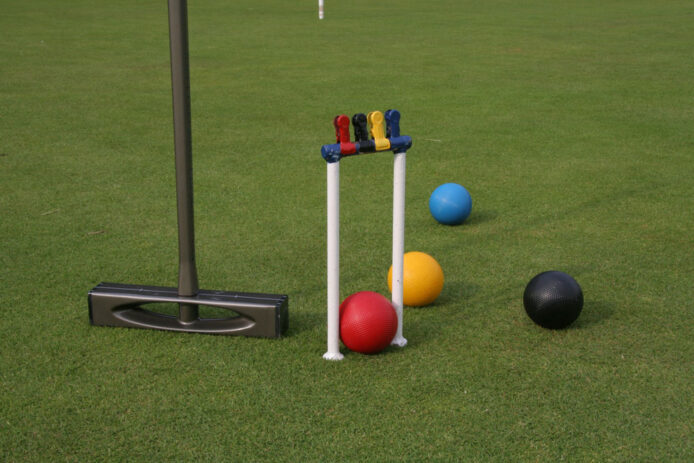 Croquet equipment of balls mallet and hoop on mown grass